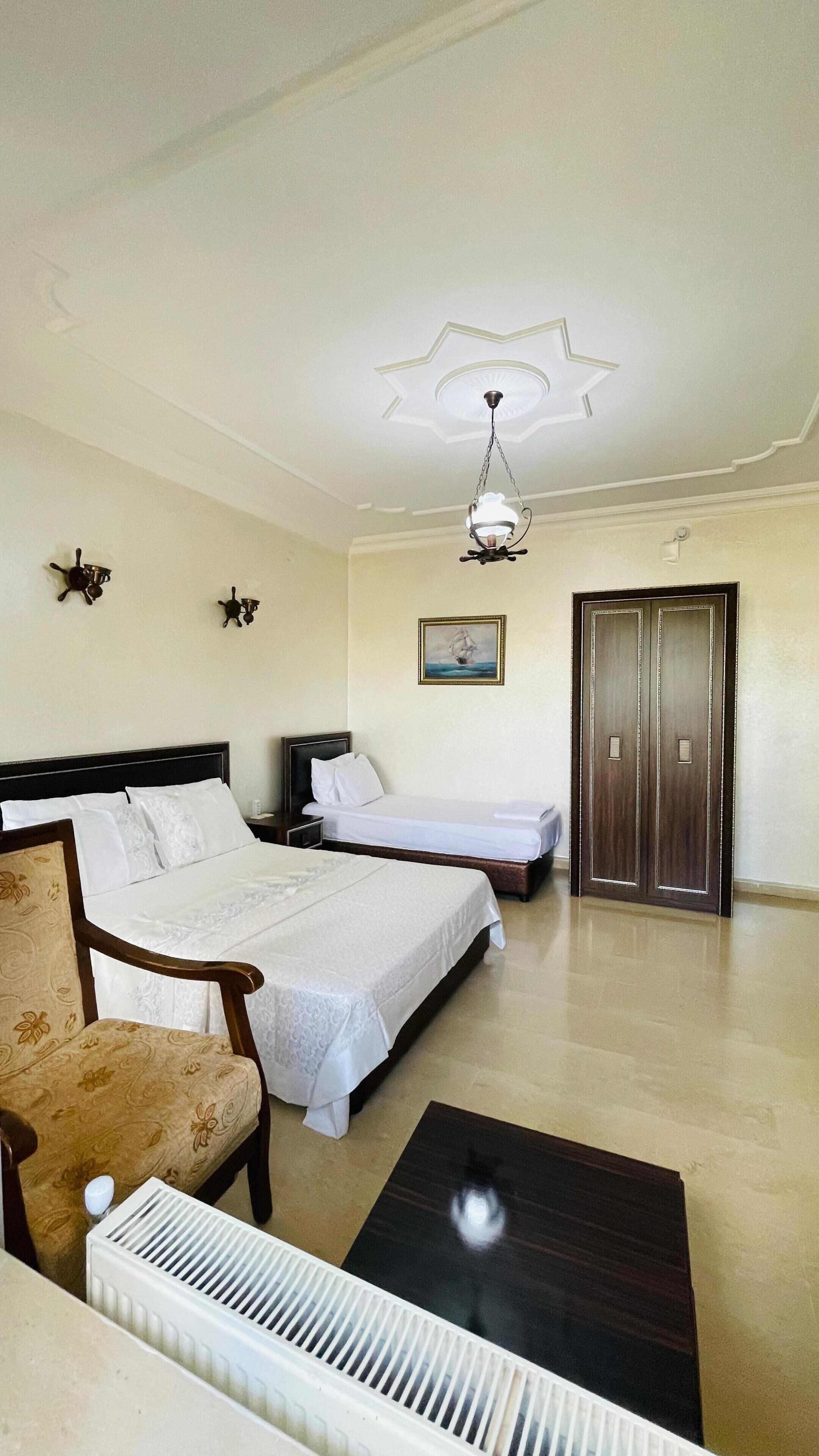 Habitación de hotel con cama, una silla, escritorio, radiador y puerta.