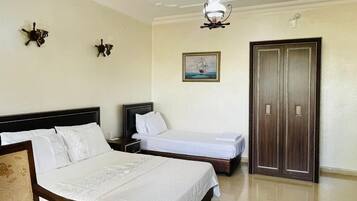 Habitación de hotel con cama, una silla, escritorio, radiador y puerta.