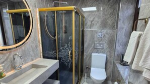 Ein modernes Badezimmer mit einer gläsernen Duschkabine, einem Waschbecken mit Marmorplatte und einer Toilette.