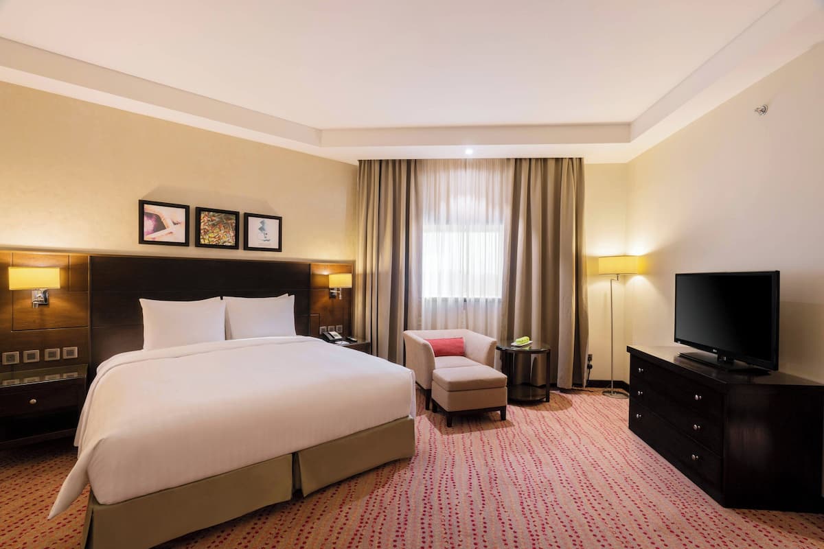 A hotel room with a large bed, a TV, a desk, and a chair.