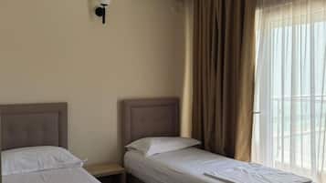 Une chambre d’hôtel avec deux lits, un climatiseur fixé au mur et une fenêtre avec des rideaux.