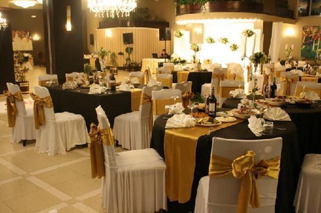Une salle de banquet avec des tables rondes, des chaises et une scène.