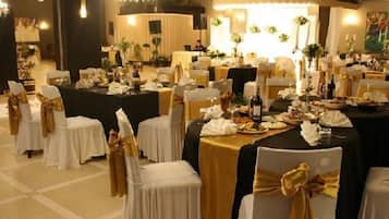 Une salle de banquet avec des tables rondes, des chaises et une scène.