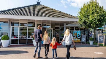 Une famille se dirige vers un bâtiment doté d’un toit en tuiles et de grandes fenêtres.