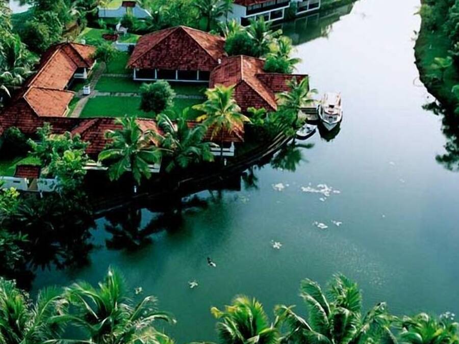 A riverside property with floating houses, surrounded by lush greenery and palm trees.