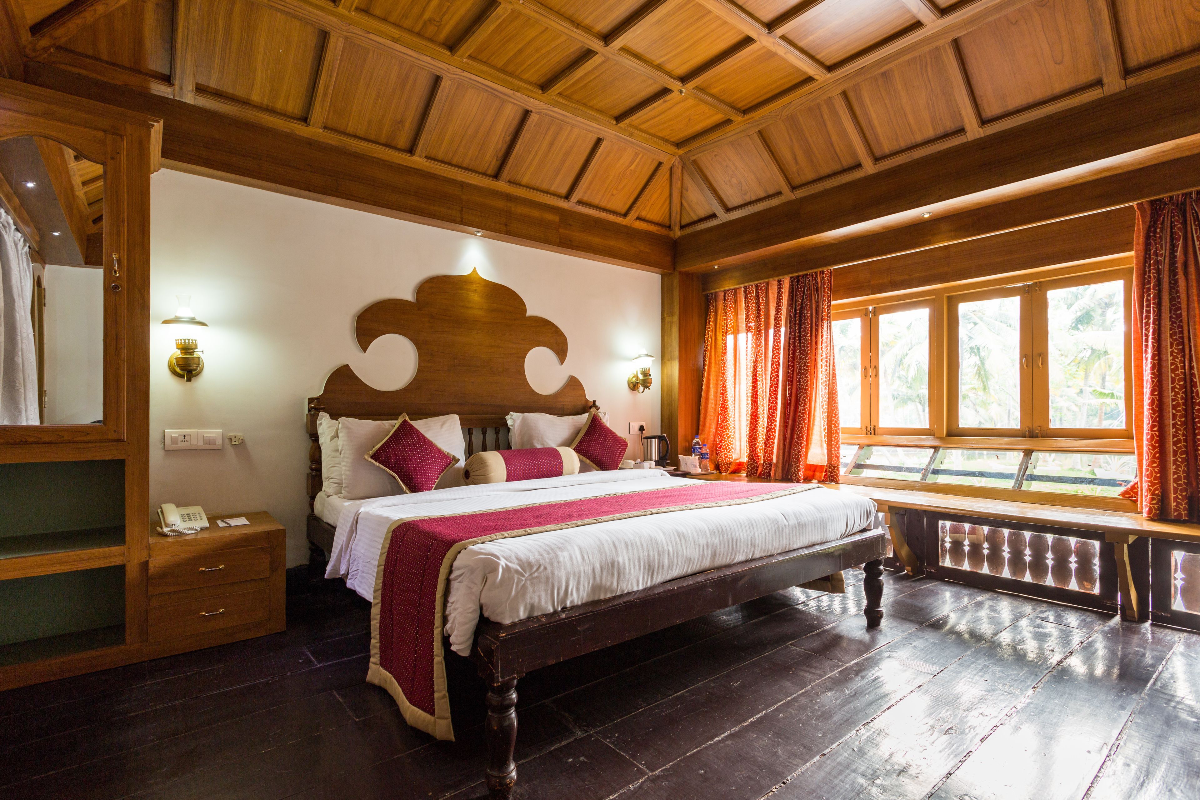 A wooden-framed bedroom with a large bed, bedside tables, and a window with curtains.