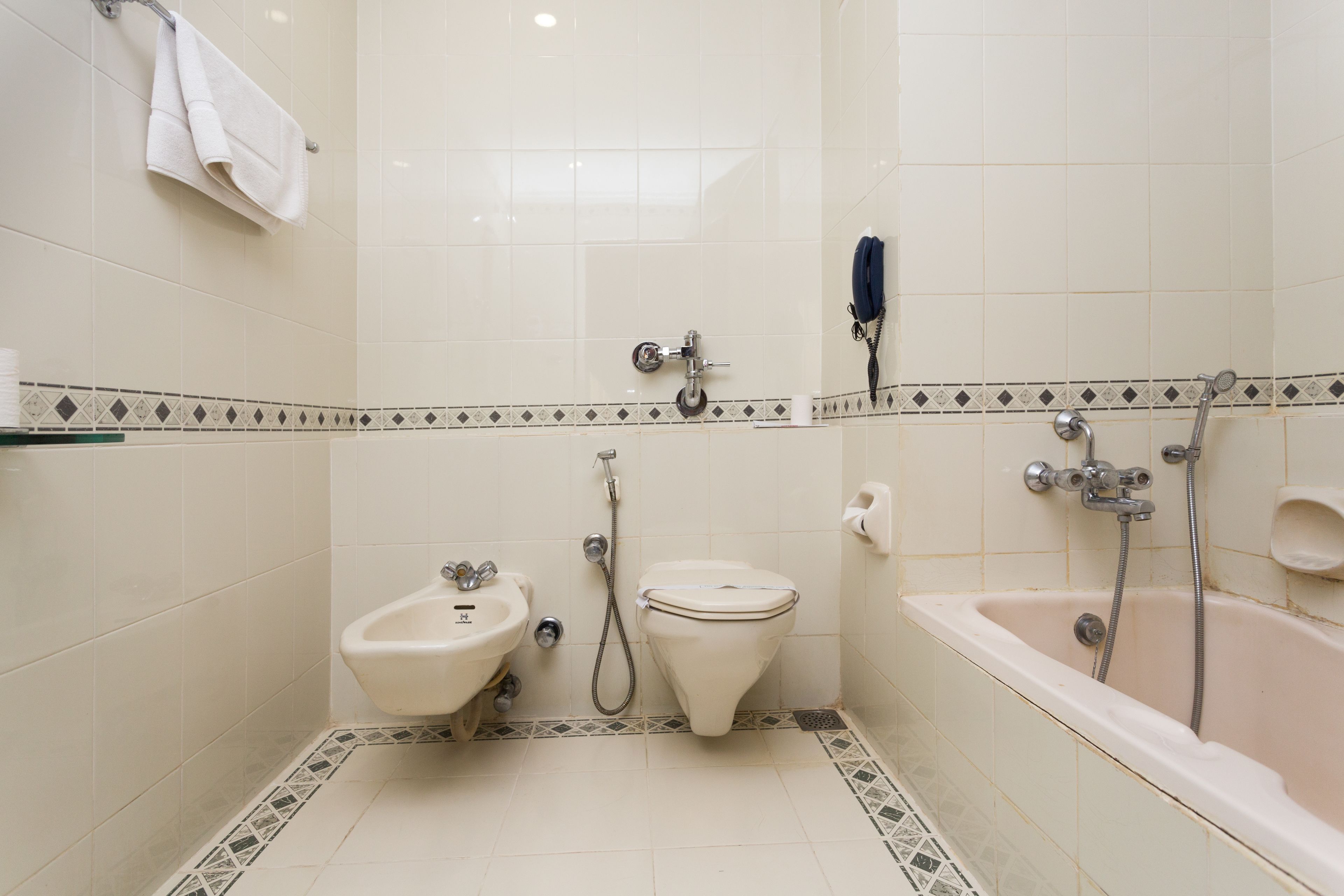Een kleine, schone badkamer met een hygiëneschuiver, toilet en bad.