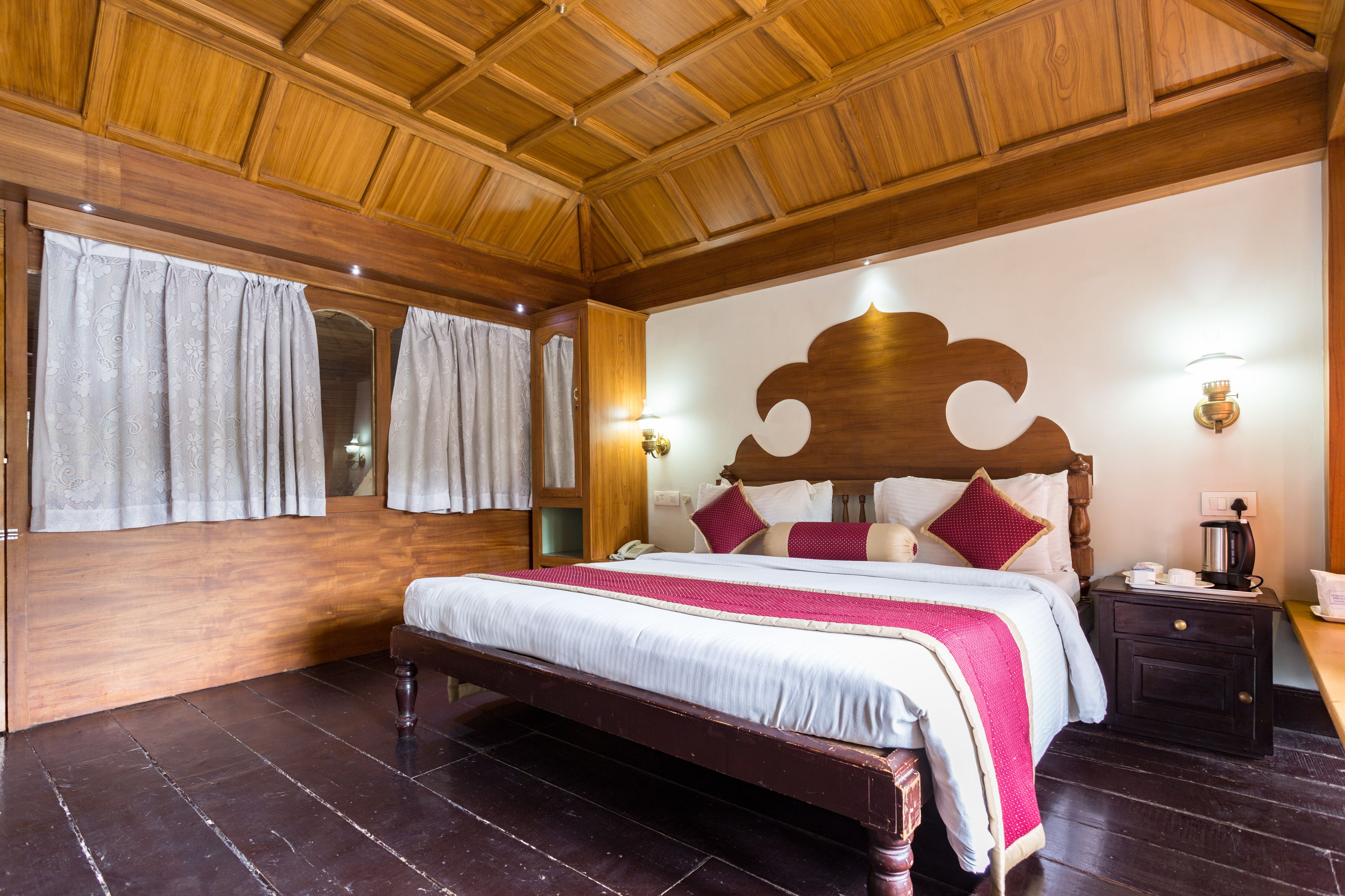 A wooden-paneled bedroom with a large bed, nightstands, and a wooden ceiling.