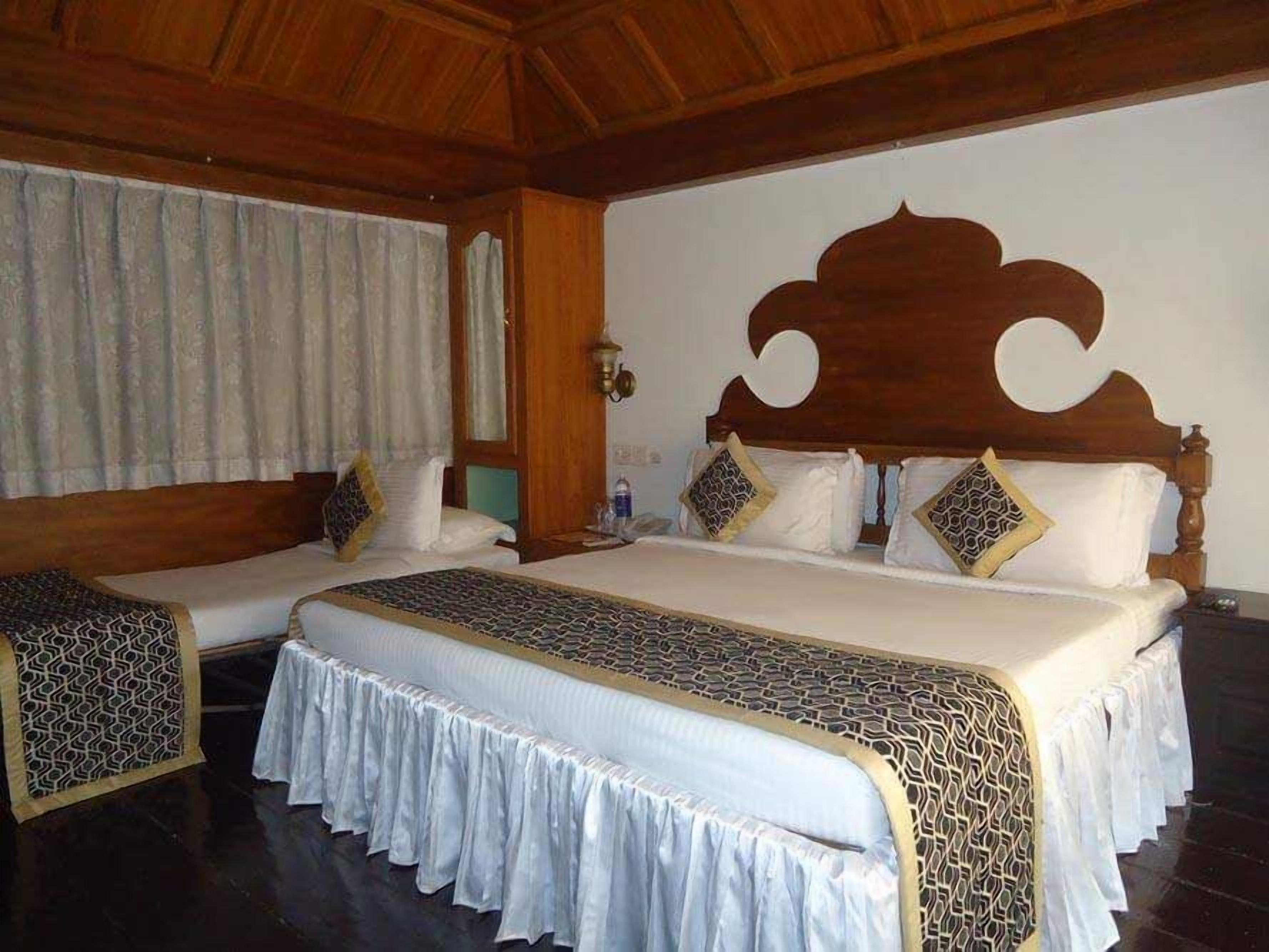 A bedroom with a large bed, a bedside table, and a window with curtains.