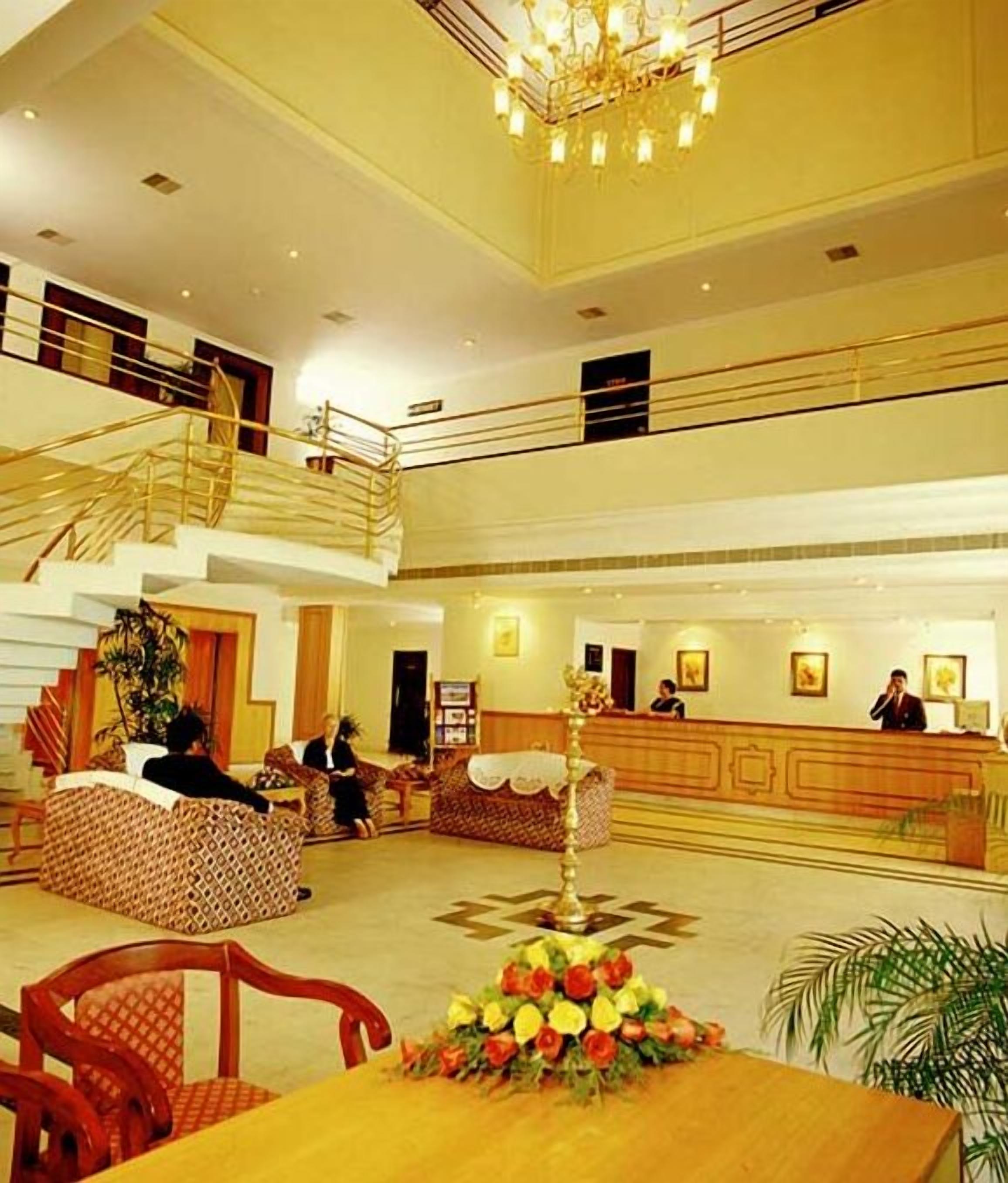 A spacious lobby with a reception desk, seating area, and a staircase leading to an upper level.