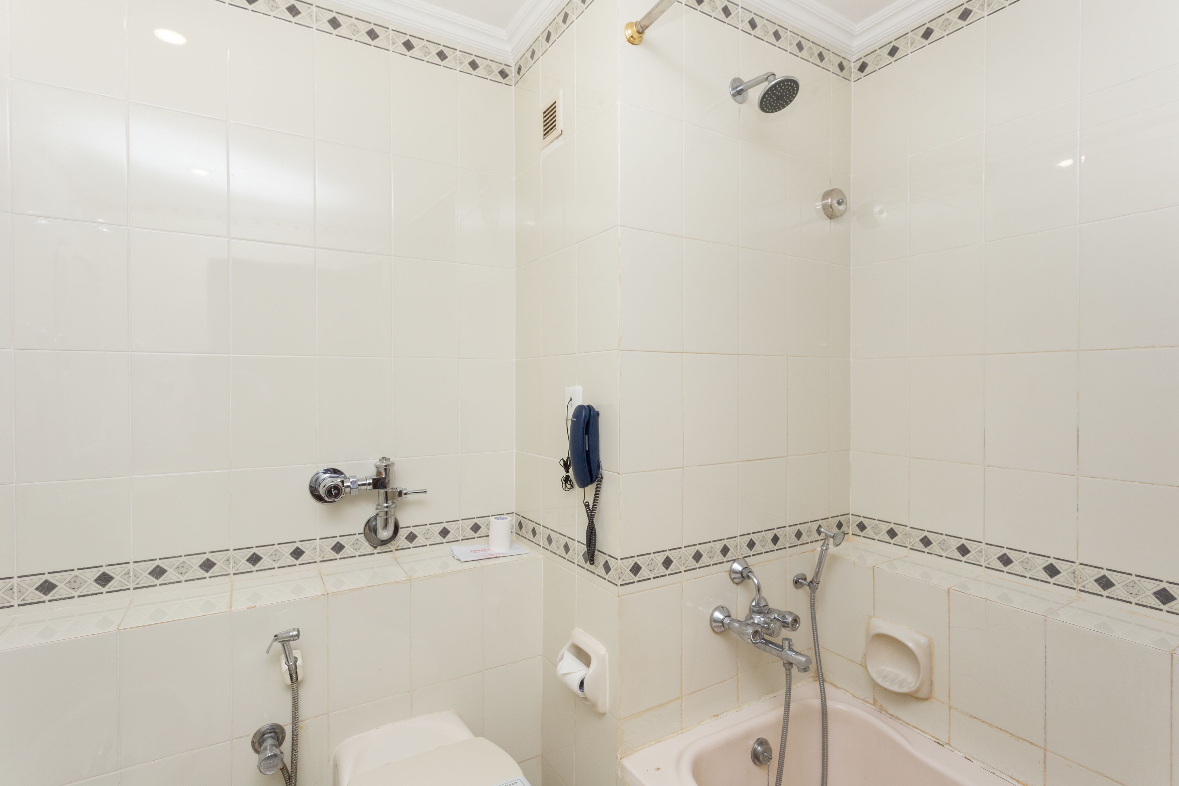 Un baño con azulejos blancos, una bañera, una ducha e inodoro.