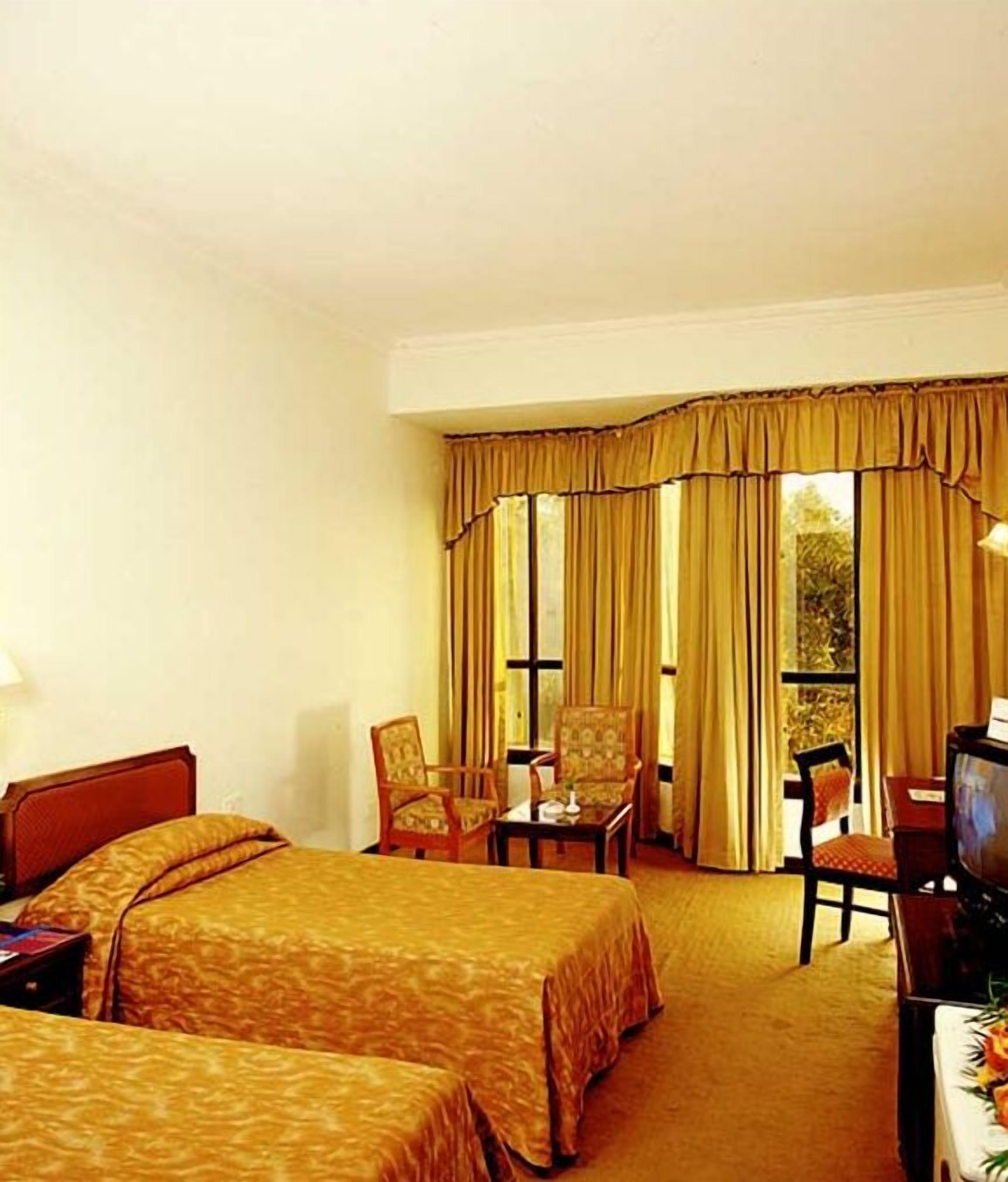 A hotel room with two beds, a desk, a television, and a chair.