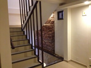 A staircase with a stone wall on one side and a plain wall on the other. - Lorenzo Suites Hotel (San Miguel de Tucuman)