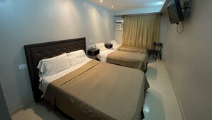 A hotel room with two beds, a flat-screen TV mounted on the wall, and a small desk with a chair. - Lorenzo Suites Hotel (San Miguel de Tucuman)
