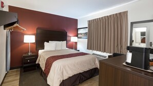 A hotel room with a bed, bedside lamps, a desk with a mirror, and a window with curtains. - Red Roof Inn Lancaster - Strasburg (Lancaster)
