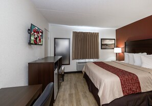 A hotel room with a bed, a desk, a chair, a television, a window with curtains, and a wall-mounted picture. - Red Roof Inn Lancaster - Strasburg (Lancaster)