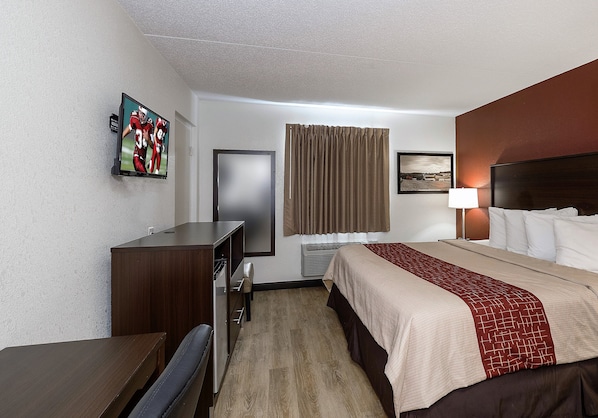 A hotel room with a bed, a desk, a chair, a television, a window with curtains, and a wall-mounted picture. - Red Roof Inn Lancaster - Strasburg (Lancaster)
