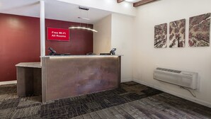 A reception area with a red wall, a reception desk, and a sign indicating free Wi-Fi. - Red Roof Inn Lancaster - Strasburg (Lancaster)