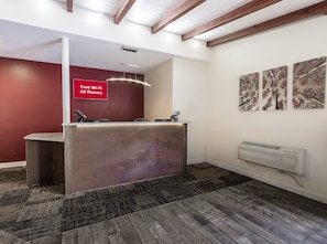 A reception area with a red wall, a reception desk, and a sign indicating free Wi-Fi. - Red Roof Inn Lancaster - Strasburg (Lancaster)
