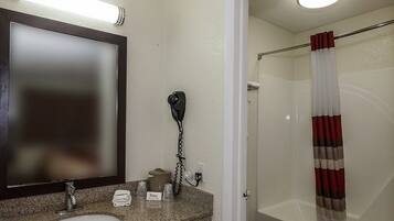 Une salle de bain avec un comptoir en granit, un miroir, un sèche-cheveux, une serviette et un rideau de douche.