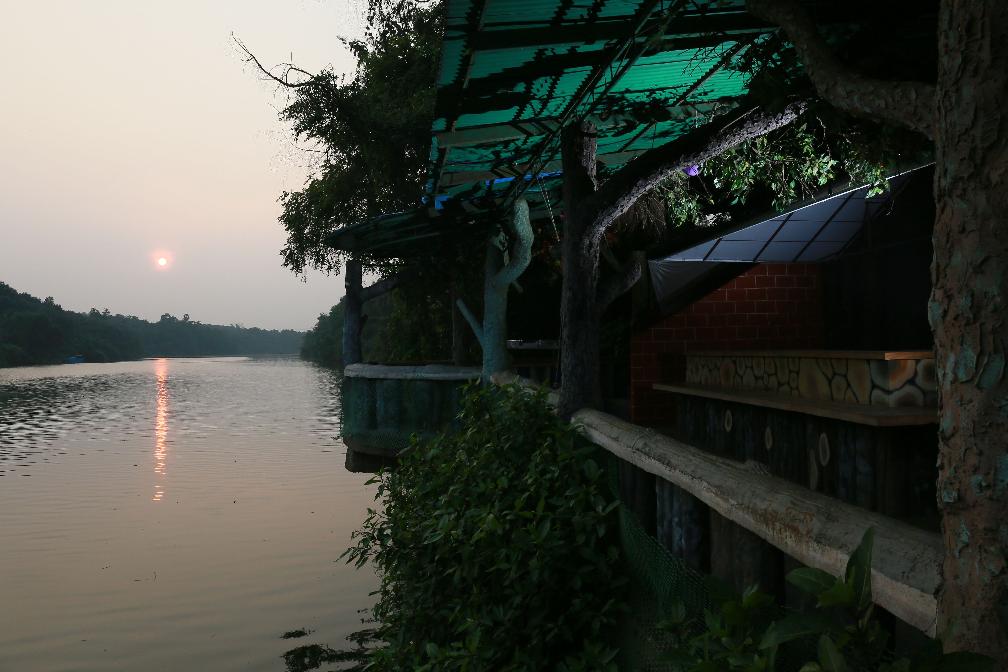 Une vue sur la rivière, avec un pont, un bâtiment à la façade en pierre et un arbre.