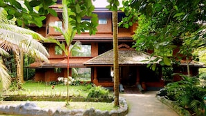 A traditional building with a tiled roof, surrounded by lush greenery and a small garden.