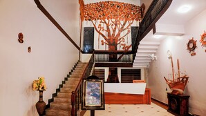 A staircase with a wooden railing, a reception desk, and a decorative ship model.