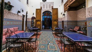 Un interior tradicional marroquí con suelos de baldosas estampadas, muebles de madera y detalles arquitectónicos ornamentales.
