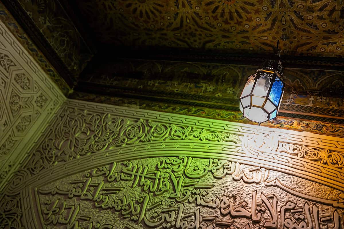 An ornate ceiling with intricate patterns and Arabic calligraphy.
