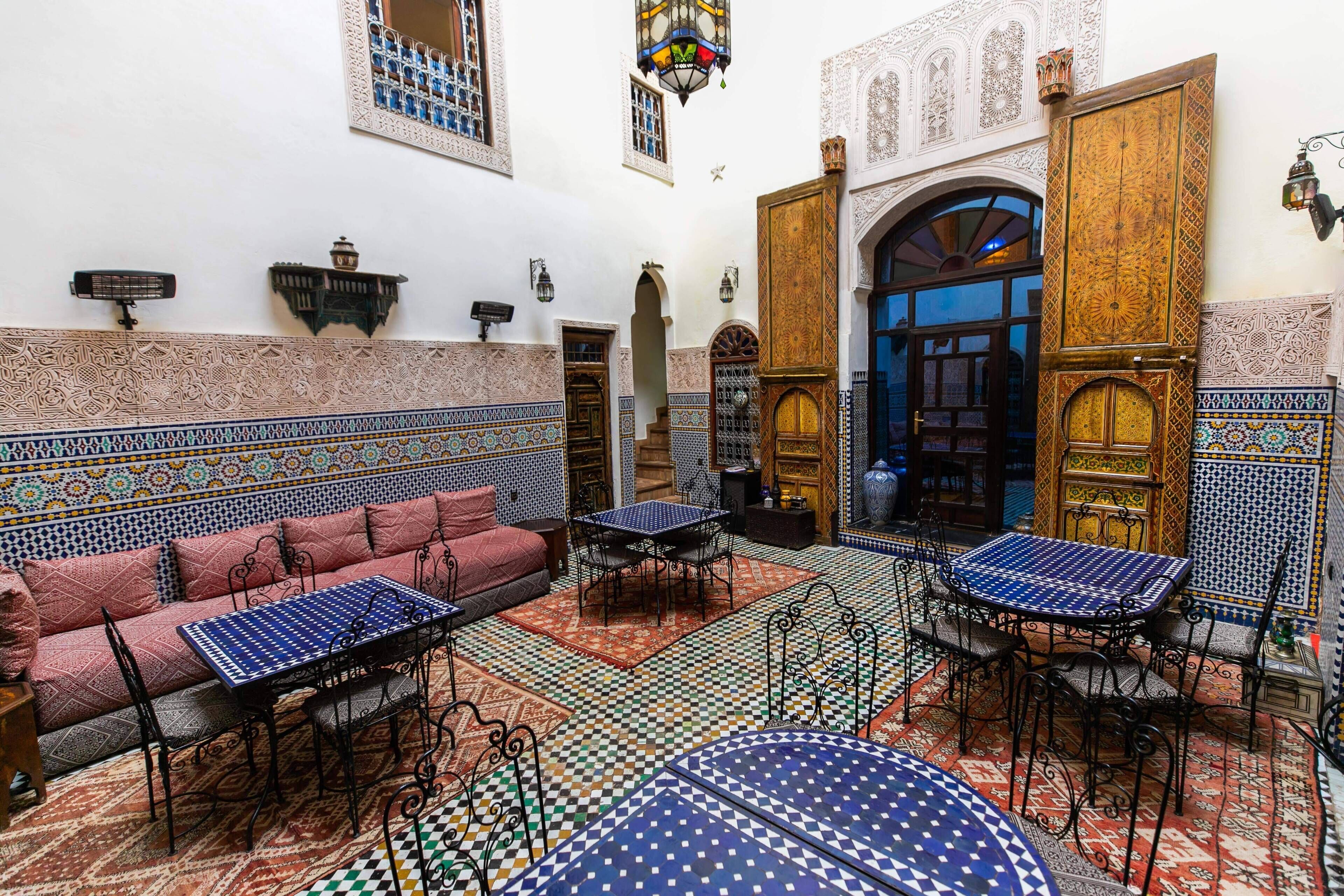 A traditional Moroccan interior with a sofa, tables, and intricate tile work.