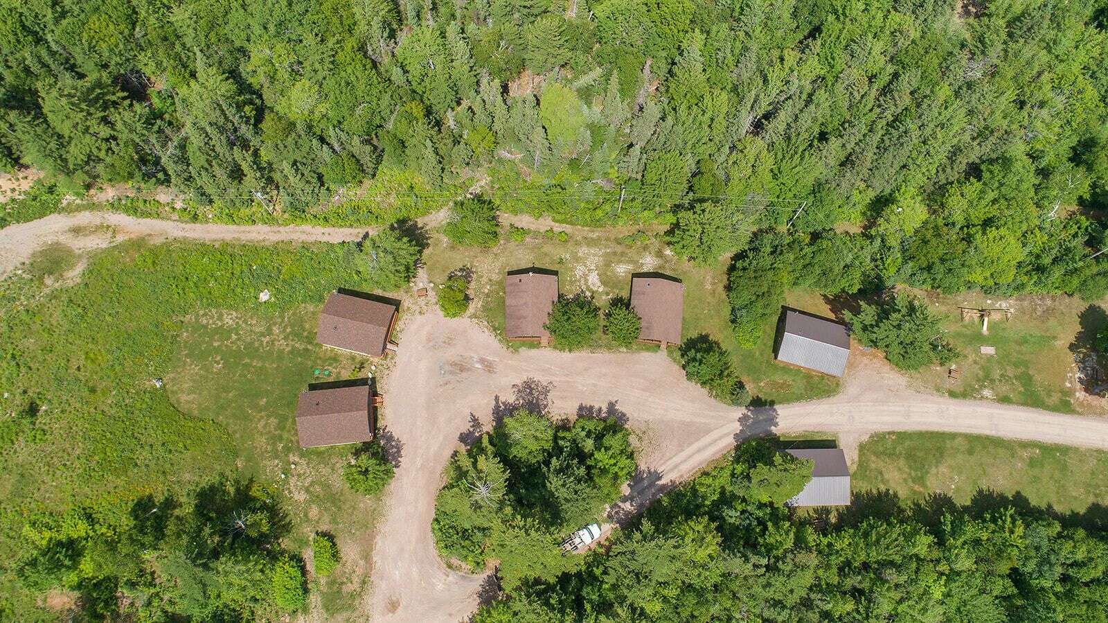 Luchtbeeld van een woonwijk met verschillende huizen, een onverharde weg en omliggend groen.