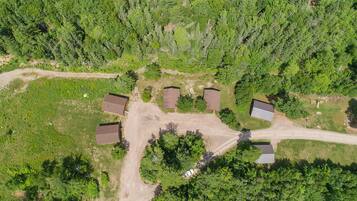 Vista aerea di una zona residenziale con diverse case, una strada sterrata e vegetazione circostante.