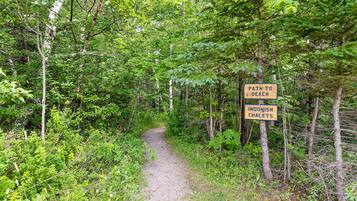 A forest path with signs indicating a path to the beach and Ingonish Chalet.