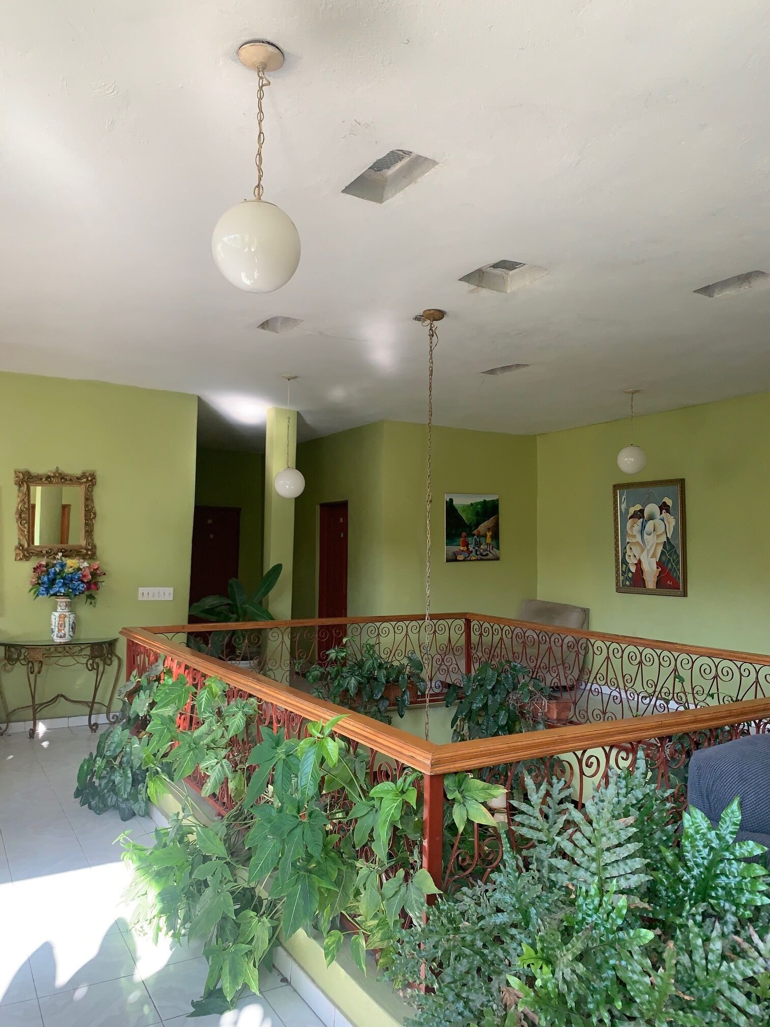 A spacious room with a wooden staircase, green walls, and a ceiling with exposed beams.