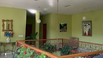 A spacious room with a wooden staircase, green walls, and a ceiling with exposed beams.