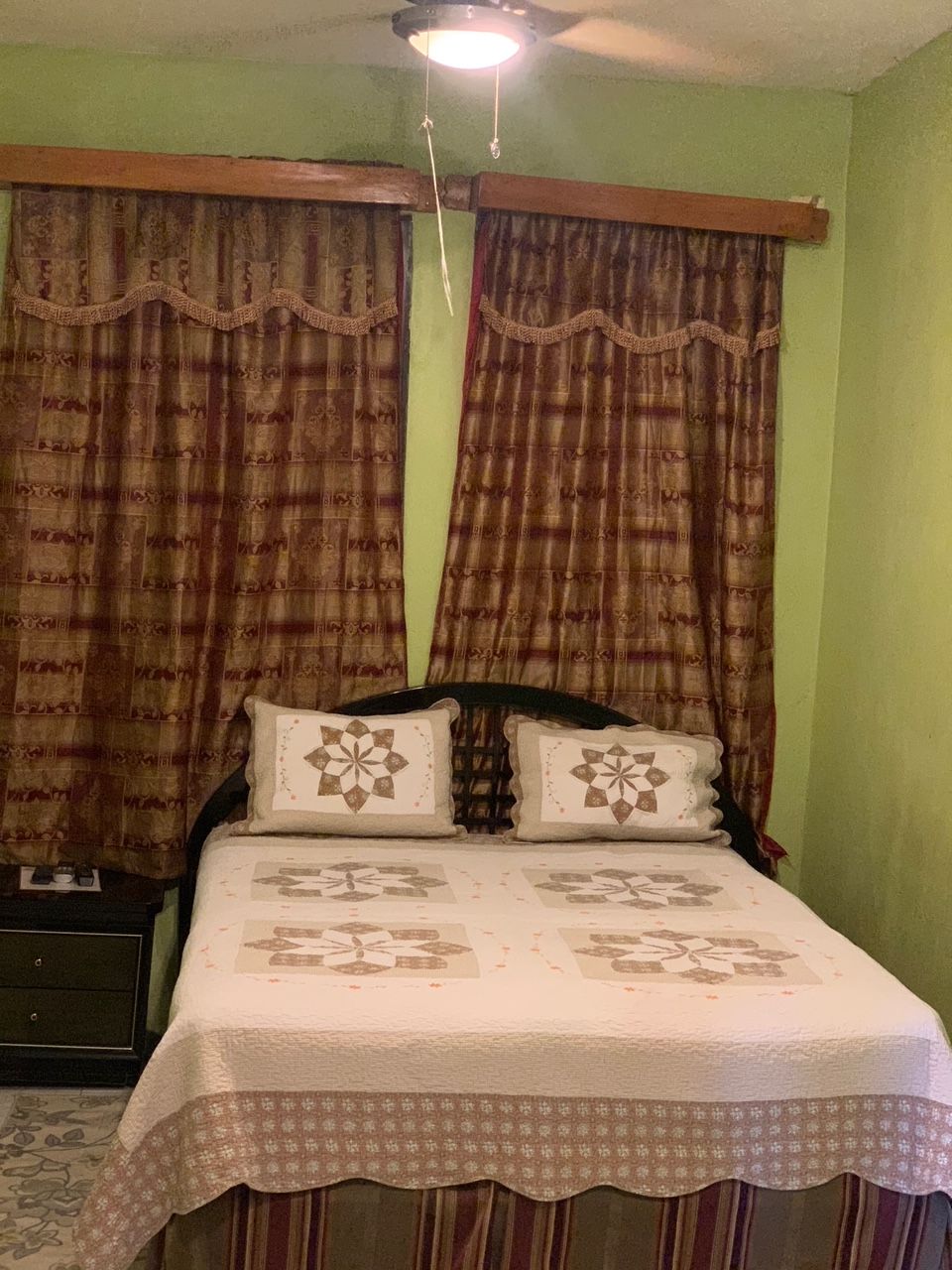 A bedroom with a bed, curtains, and a ceiling light fixture.