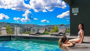 A swimming pool with lounge chairs and a view of mountains.