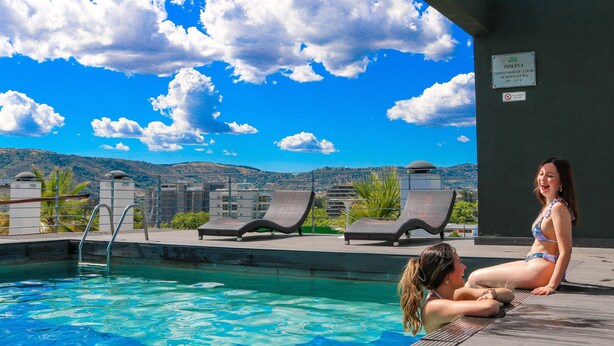 A swimming pool with lounge chairs and a view of mountains.