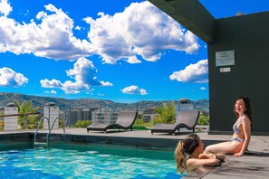 A swimming pool with lounge chairs and a view of mountains.