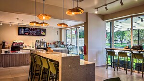 A modern cafe with a bar area, large windows, and a menu display.