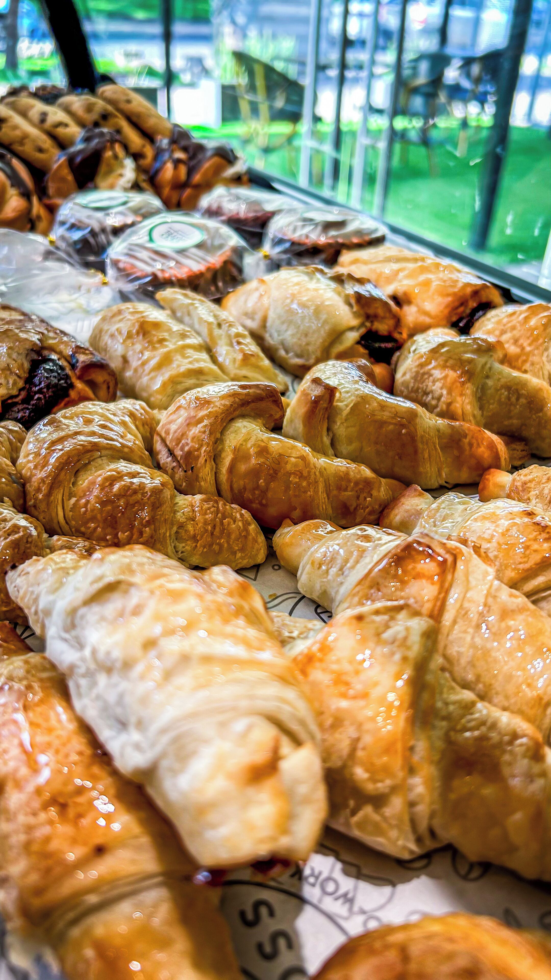 Una exhibición de diversos pasteles, incluyendo croissants y otras delicias horneadas, dispuestas sobre un mostrador.