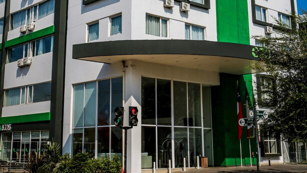 A modern hotel building with a green vertical stripe, multiple floors, and large windows.