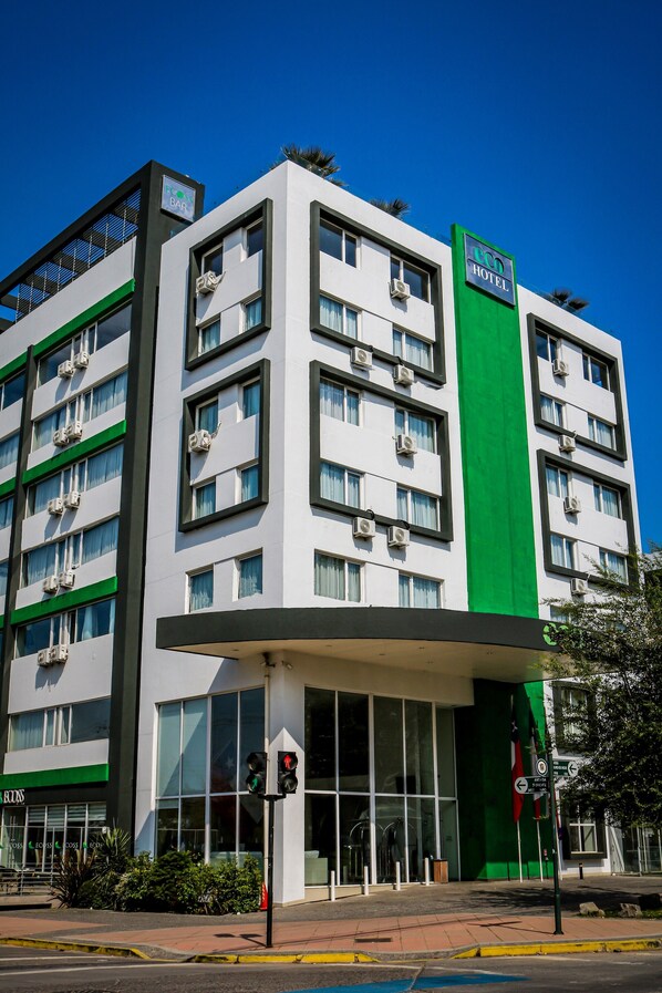 A modern hotel building with a green vertical stripe, multiple floors, and large windows.