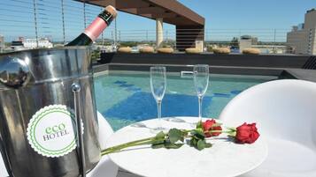 Een dakzwembad met champagnekoeler, waarop 'eco hotel' staat, en twee glazen op een tafel met rozen.