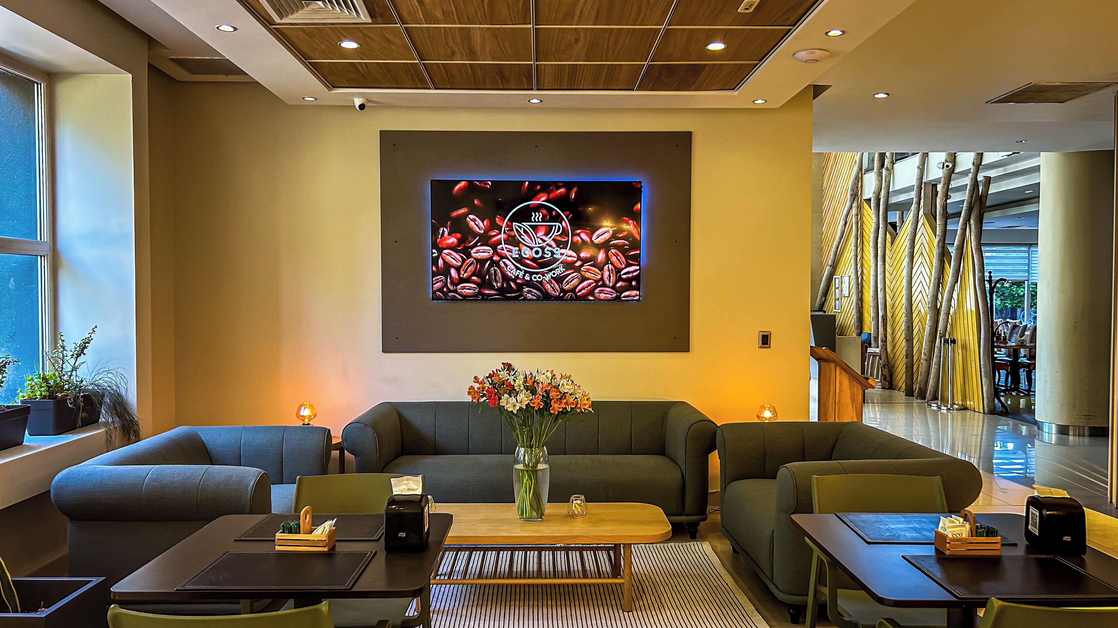 A modern lobby with a large coffee-themed wall art, comfortable seating, and a view of the outdoor area.