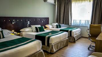 A hotel room with two beds, a desk, a chair, and a window with curtains.