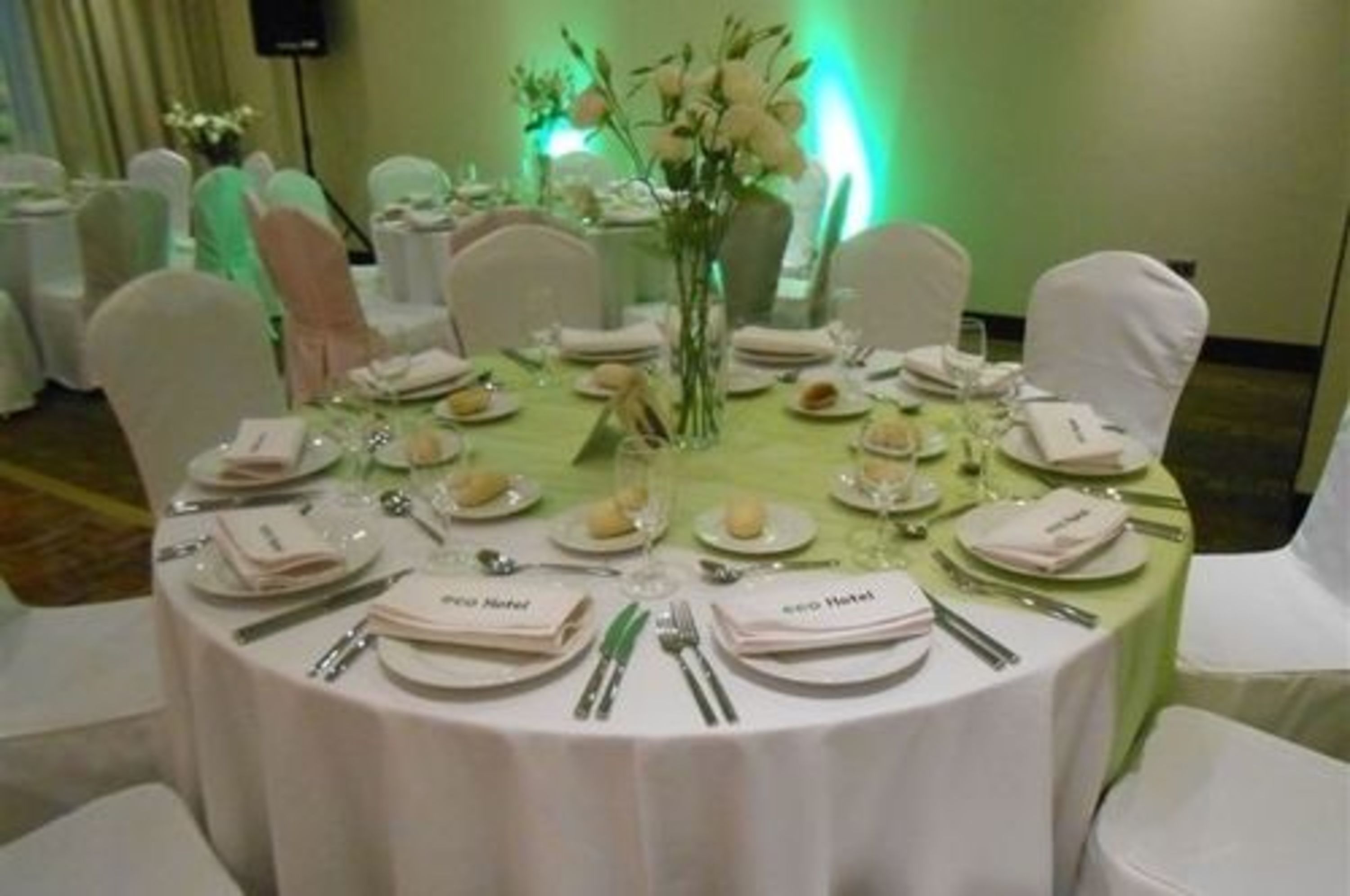 A round table set for a formal event with name cards, plates, and cutlery.