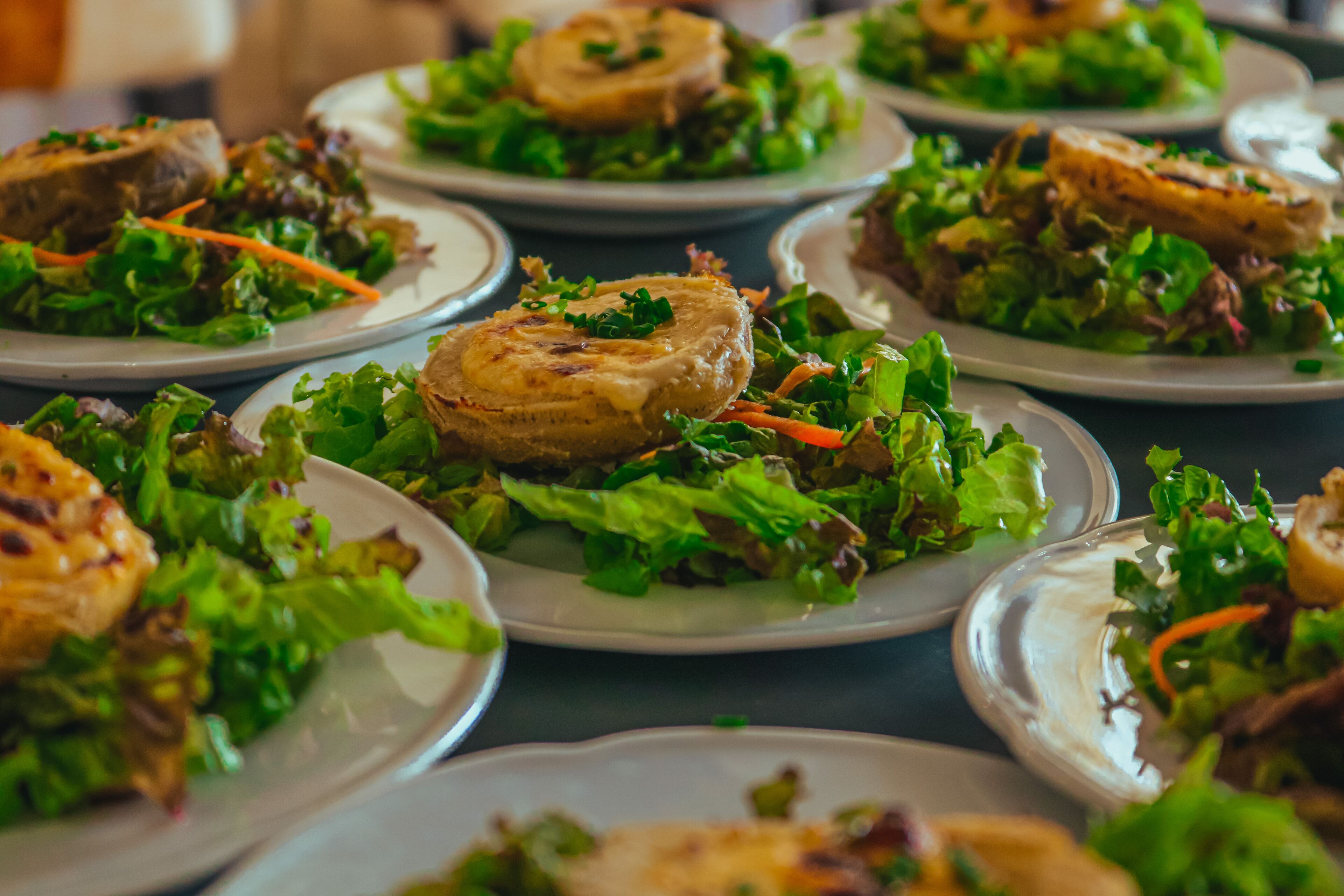 A table with multiple plates of food, each containing a piece of meat and a salad.
