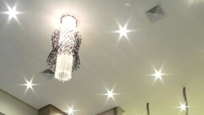 A modern interior with a unique light fixture, a reception desk, and a staircase with a minimalist design.