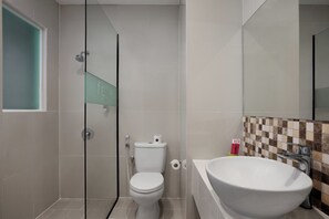 Et badeværelse med toilet, bruser og håndvask.